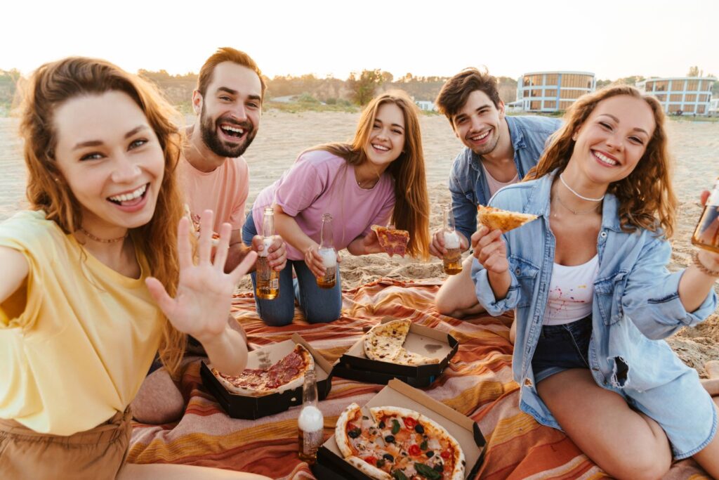 group of friends enjoying pizza on the beach